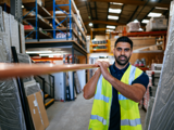 Progress colleague in warehouse carrying a long pie on his shoulder smiling 