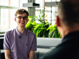 "image shows intern George smiling at work talking to colleague"