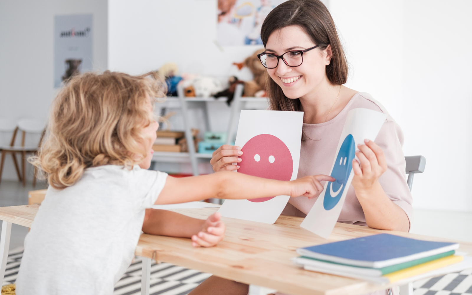 shows a small child pointing to a mood chart to express his feelings to his mother 