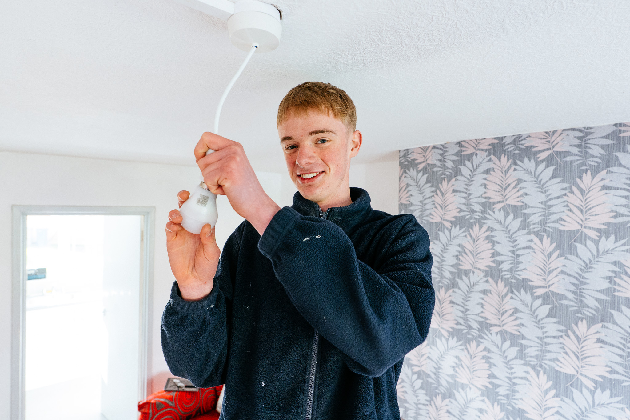 An apprentice electrician changes a light fitting