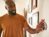 Male turning down his heating dial on the wall