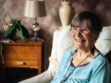tenant smiling for photo in arm chair in her home 