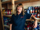 employee smiling in front of stocked shelves at the Fylde community hub