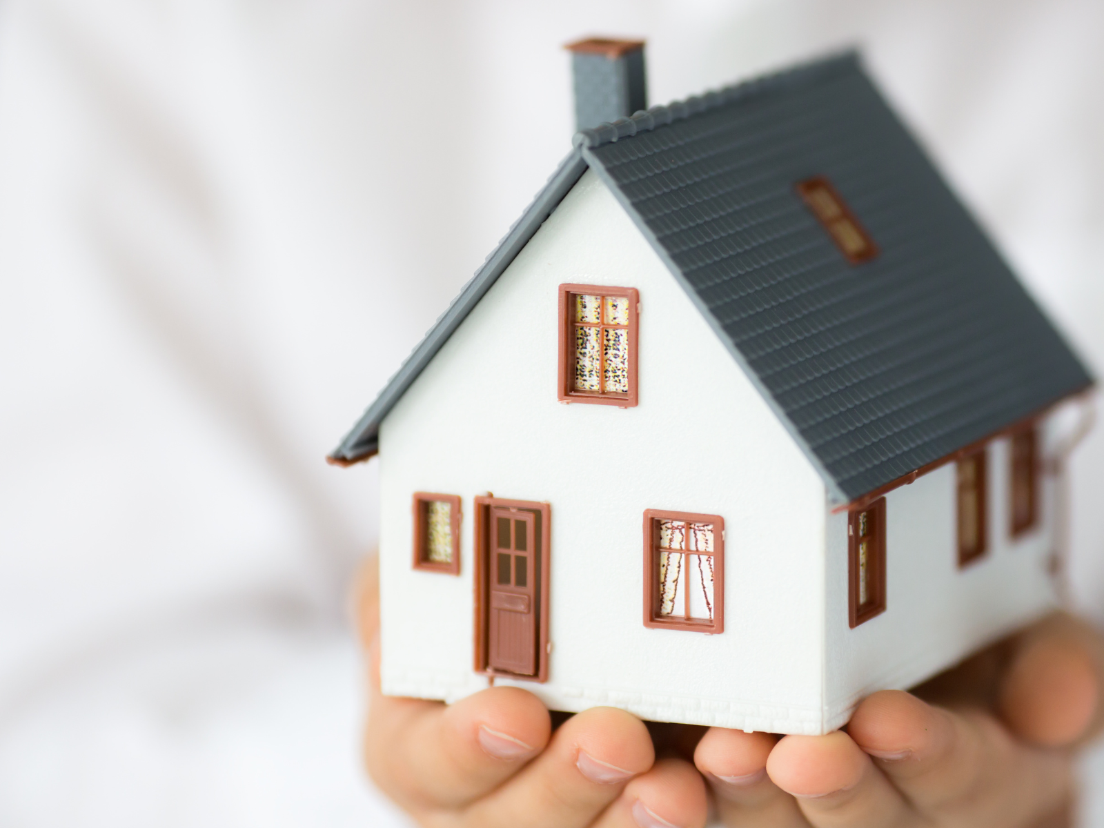 Hands holding a model of a white house