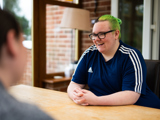tenant sitting at desk laughing at something someone is saying